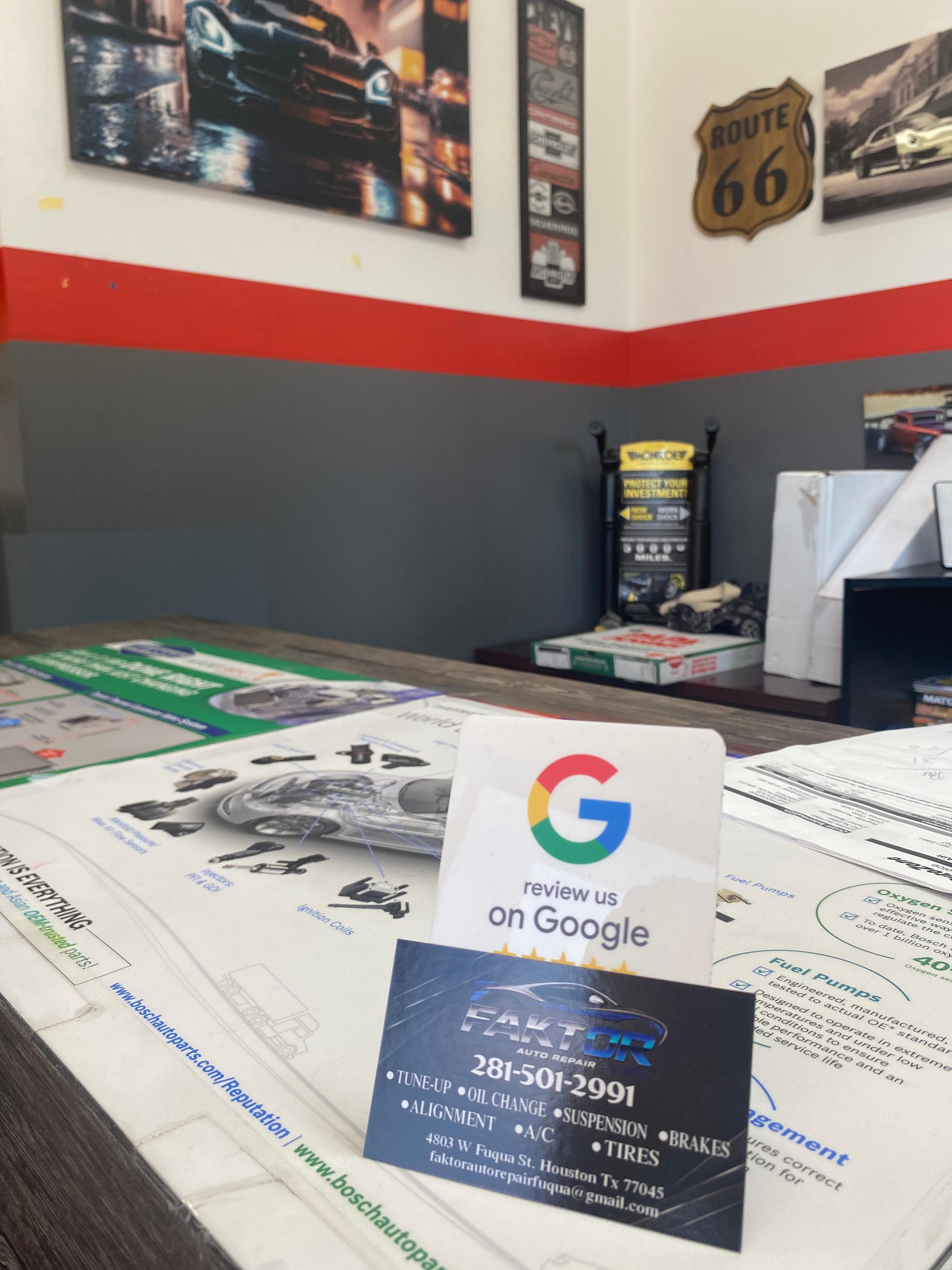 Área de recepción de Faktor Auto Repair con decoración temática de autos y tarjeta de reseñas de Google